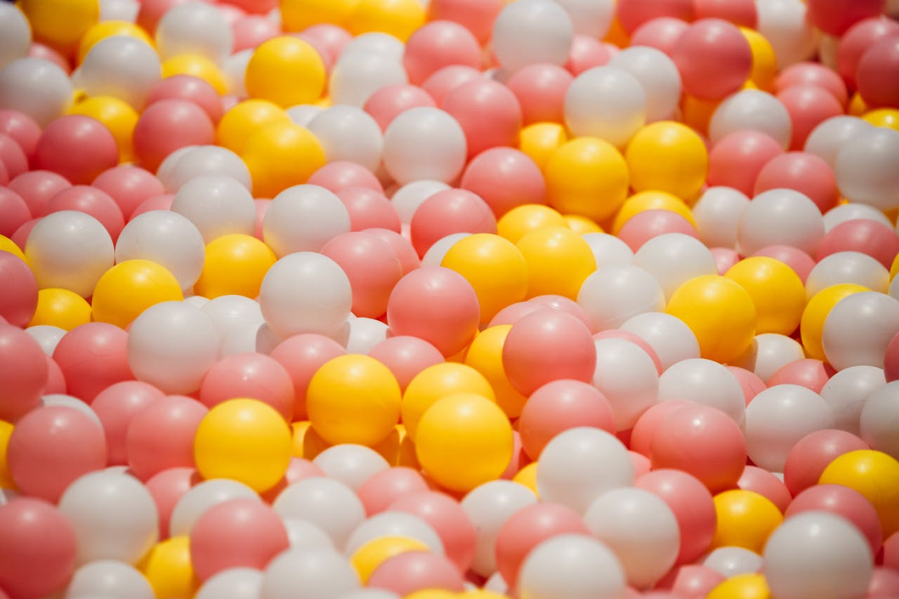 services-01 A vibrant close-up of pink, white, and yellow ball pit balls creating a colorful pattern.