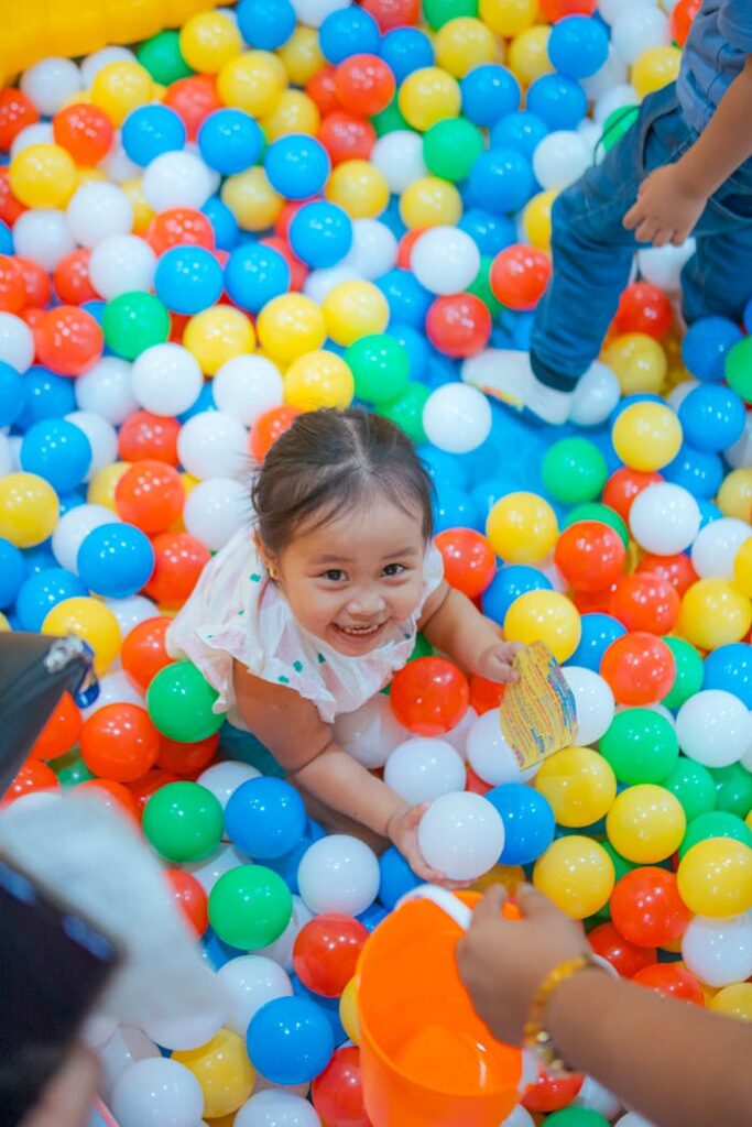 A happy child enjoying playtime in a vibrant, colorful ball pit indoor setting.