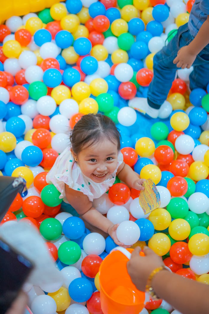 services-02 A happy child enjoying playtime in a vibrant, colorful ball pit indoor setting.