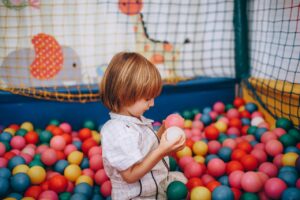 Cute child enjoying a colorful ball pit at an indoor play area, surrounded by vibrant colors.