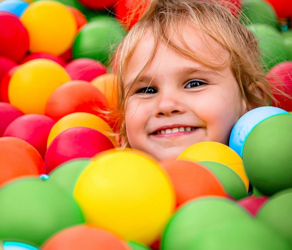 pexels photo 33198674 Smiling child having fun in a colorful ball pit, showcasing happiness and playtime.